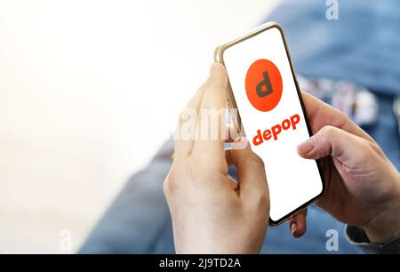 Rome, Italie, mars 2022: Une femme naviguant sur le site Internet de la société Depop sur son téléphone dans son salon par un beau temps. Rédactionnel. Maquette réaliste Banque D'Images