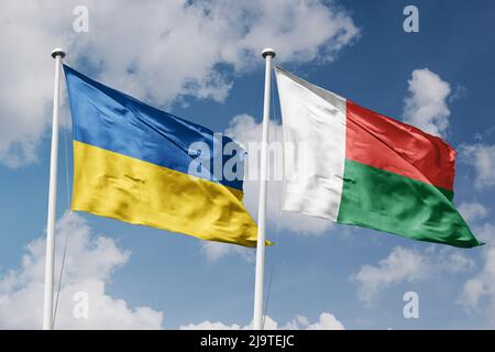Ukraine et Madagascar deux drapeaux sur les mâts et bleu nuageux fond ciel Banque D'Images