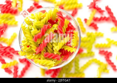 Gros plan de Fusille et de rotini dans un bol en verre sur blanc. Pâtes colorata Banque D'Images