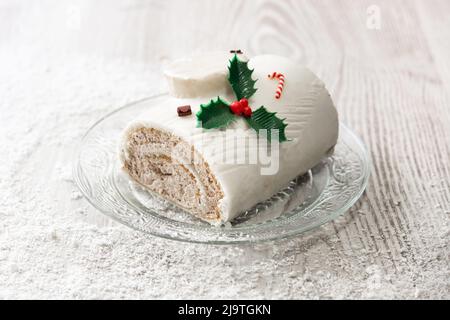 Gâteau de bois de yule au chocolat blanc avec ornement sur table en bois et neige Banque D'Images