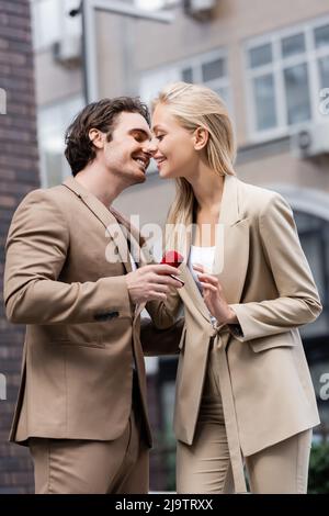 homme souriant faisant une proposition de mariage à une femme blonde élégante dans la rue urbaine Banque D'Images
