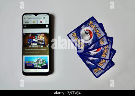 Prague, République Tchèque - avril 3 2022 : verso des cartes Pokemon et smartphone avec une version en ligne ouverte du jeu Pokemon Trading Card. Banque D'Images