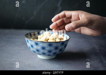 cueillez à la main la noix de cajou dans un bol sur la table Banque D'Images