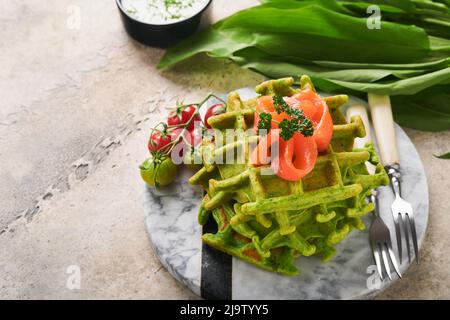 Gaufres belges vertes. Épinards ou ail sauvage ou gaufres au pesto avec saumon rouge et sauce à la crème sur fond de table en béton gris. Délicieux petit déjeuner, Banque D'Images