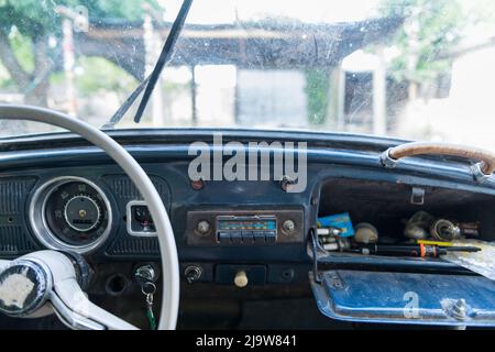 détails du tableau de bord d'un ancien coléoptère volkswagen où le volant blanc et la boîte à gants de la voiture sont visibles au premier plan. Banque D'Images