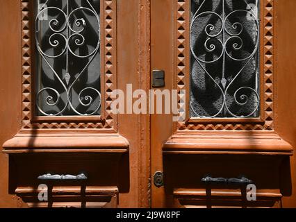 Ancienne maison néoclassique entrée avant porte en bois avec grilles en fer forgé fabriquées à la main et poignées anciennes en laiton. Banque D'Images