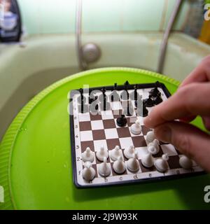 L'amant des échecs aime les débuts de Reti dans un bain à remous, le plaisir physique et intellectuel de blenging, la plate-forme d'échecs sur un bol en plastique vert retourné Banque D'Images