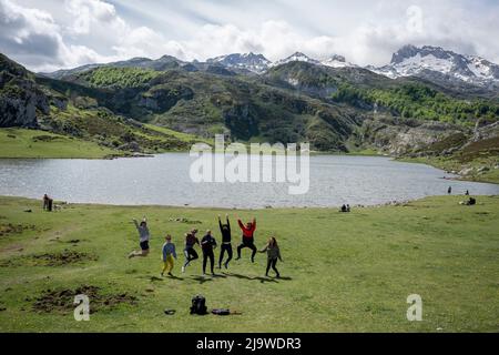 Les visiteurs sautent pour prendre des photos au-dessus du Lago (lac) espagnol la Ecina dans le parc national Picos de Europa, le 16th mai 2022, Covadonga, montagnes Picos, Asturies, Espagne. Les lacs Enol et Ercina sont les plus grands lacs de Covadonga - deux lacs glaciaires adjacents situés à plus de 1000 mètres au-dessus du niveau de la mer. Banque D'Images