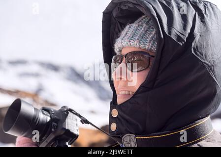 FEMME PRENANT DES PHOTOS DANS LA MONTAGNE ENNEIGÉE. PHOTOGRAPHIE HORIZONTALE. Banque D'Images