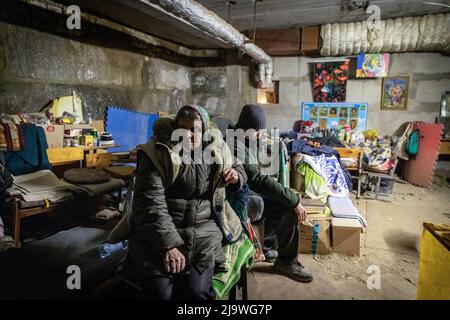 Sasha (18 ans) et sa grand-mère qui vit aujourd'hui dans un bunker souterrain à Kharkiv. Une ancienne école est maintenant transformée en bunker, car elle accueille plus de 100 000 citoyens vivant dans le district de Saltivka à Kharkiv, qui ont été contraints d'adopter une nouvelle vie sous terre dans des bunkers sans électricité ni eau, dans le cadre de bombardements intensifs et constants de frappes aériennes russes. Banque D'Images