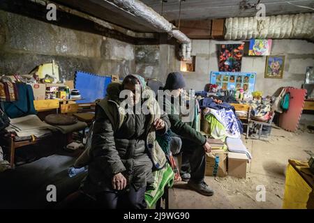 Sasha (18 ans) et sa grand-mère qui vit aujourd'hui dans un bunker souterrain à Kharkiv. Une ancienne école est maintenant transformée en bunker, car elle accueille plus de 100 000 citoyens vivant dans le district de Saltivka à Kharkiv, qui ont été contraints d'adopter une nouvelle vie sous terre dans des bunkers sans électricité ni eau, dans le cadre de bombardements intensifs et constants de frappes aériennes russes. Banque D'Images