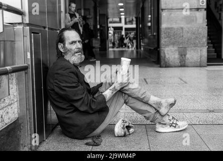 Un homme sans domicile avec le pied infecté s'assit supplier de l'argent à l'extérieur de Victoria Station, Londres, Royaume-Uni Banque D'Images