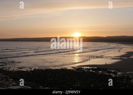 Le soleil descendant sur le bord ouest.Sun set et surfeurs à Lahinch dans l'ouest de l'Irlande. Banque D'Images