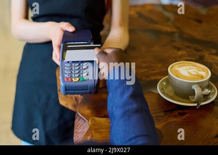 Gros plan de l'homme payant avec une carte de crédit pour son café tout en étant assis à table dans le café Banque D'Images