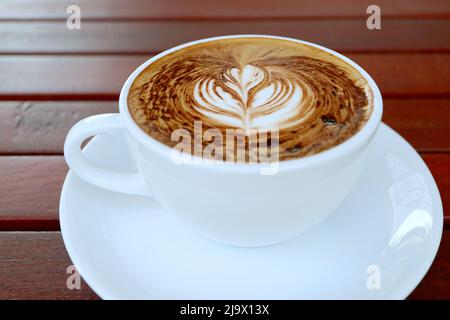 Préparez un café Cappuccino chaud avec un latte d'art appétissant sur une table en bois Banque D'Images