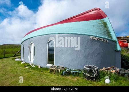 Construction de hangar à bateaux originaux, île de Rousay utilisant un bateau de pêche retourné comme toit pour un bâtiment avec vue sur Wyre Sound, Orkney, Écosse. Banque D'Images