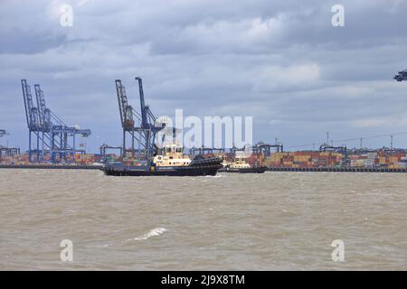 Remorqueur Svitzer Deben aidant un navire à conteneurs à quitter le port de Felixstowe dans des conditions météorologiques défavorables. Banque D'Images