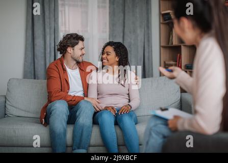 Un jeune homme européen heureux et une femme afro-américaine se regardent sur consultation avec le psychologue Banque D'Images