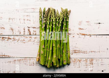 Au-dessus des épis d'asperges fraîches sur une table blanche rustique. Banque D'Images