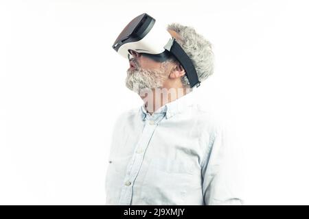 Réalité virtuelle pour tous. Un homme adulte européen aux cheveux argentés dans une chemise portant des lunettes VR professionnelles sur fond blanc. Tir isolé. Photo de haute qualité Banque D'Images