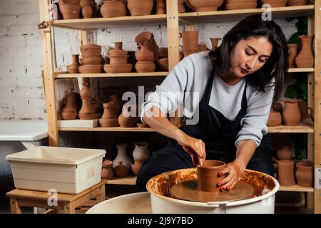 Belle potter maître femme moules de pot d'argile en mai. Femelle étudiant sculpteur travaille avec l'argile sur une roue de potier et à la table avec le Banque D'Images