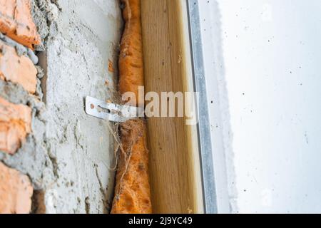 Fixation d'une fenêtre en plastique sur un mur de blocs de béton cellulaire. Fenêtre sur un site de construction abandonné dans une toile d'araignée. Ancienne et nouvelle mousse de montage Banque D'Images