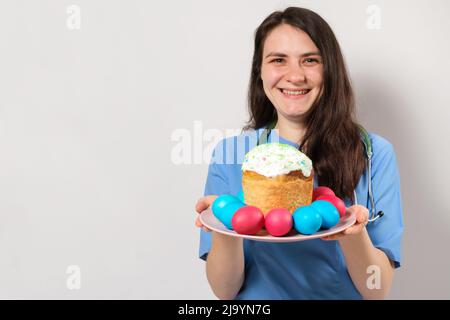 Le médecin tient un gâteau de Pâques et sourit, un endroit pour le texte. Pâques médicales Banque D'Images