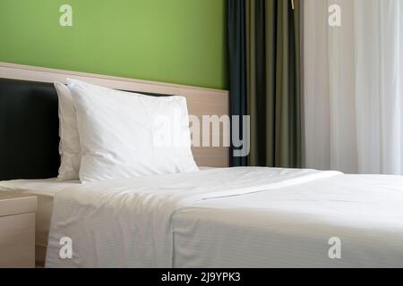 Décoration simple et moderne de la chambre d'hôtel avec lit, mur vert, style neutre d'affaires Banque D'Images