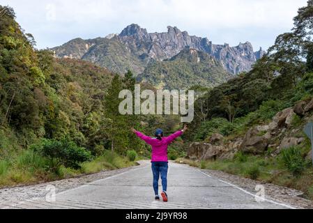 Vue arrière d'une femme avec le bras levé devant le mont Kinabalu à Kundassang Sabah Bornéo en Malaisie Banque D'Images