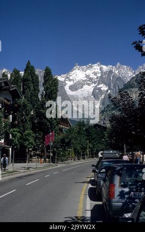 Les voitures sont stationnées sur la via Regionale. En arrière-plan, le massif du Mont blanc avec le glacier de Brenva. Courmayeur, Valle d'Aoste, Italie, 1990 Banque D'Images