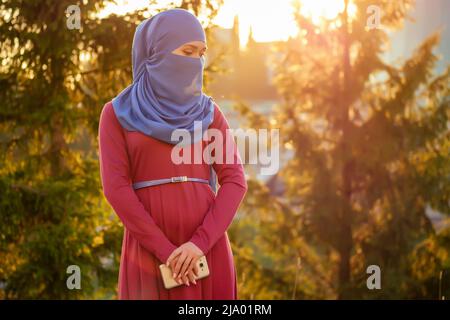 Portrait d'une belle femme musulmane aux yeux verts portant un foulard bleu visage fermé couvert d'aveil arrière-plan arbres forestiers dans le parc Banque D'Images