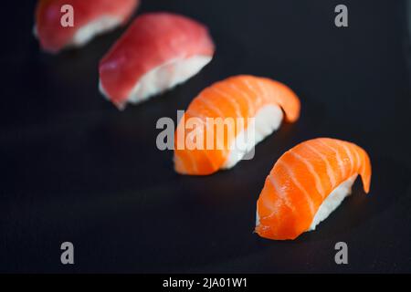 Quatre sushis préparés sur fond noir. Concept de nourriture japonaise et de saine alimentation sur table en pierre. Banque D'Images