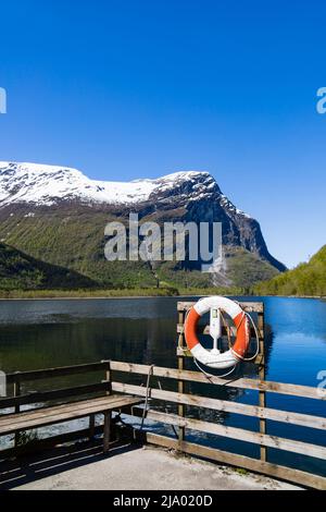 Ceinture de vie sur la jetée en regardant le lac Lovatnet de Kjenndalstova, Norvège. Sommets enneigés et eaux bleues claires. Banque D'Images