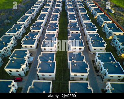 Vue panoramique d'un grand nombre de petits hôtels gris appartements identiques dans une petite ville avec des rues vides et des voitures modernes, entouré par Banque D'Images