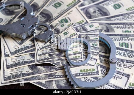 Argent en dollars américains, menottes réelles. Le concept d'arrestation, de corruption, de mise en liberté sous caution, de crime, de corruption ou de fraude Banque D'Images