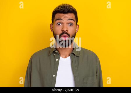 Photo de choqué joli gars habillé vert chemise grands yeux isolé couleur jaune fond Banque D'Images
