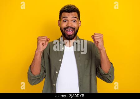 Photo d'un mignon gars excités habillé chemise verte hurlant poings Rising Fists isolé couleur jaune arrière-plan Banque D'Images