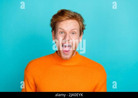 Photo d'un joli gars impressionné vêtu d'un chandail orange à bouche ouverte isolé couleur turquoise arrière-plan Banque D'Images