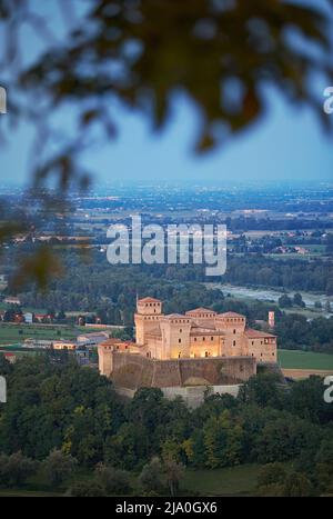 Le château médiéval de Torrechiara s'illuminait la nuit, avec la vallée de Parme en arrière-plan, Langhirano, Parme, Emilia Romagna, Italie. Banque D'Images