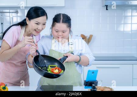 Asiatique personne avec le syndrome de Down cuisiner avec maman. Croissance du cerveau apprentissage famille amour intelligence cuisine Banque D'Images