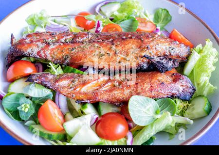 Deux filets de maquereau fumé fraîchement cuits servis avec une salade fraîche. Le poisson gras est une bonne option de repas sain riche en acides gras oméga 3 Banque D'Images