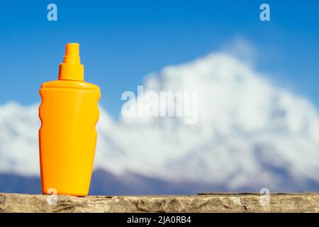 crème solaire dans une bouteille d'orange sur fond de montagne. le concept de prévention du cancer de la peau et l'utilisation de la crème solaire dans les montagnes. Banque D'Images