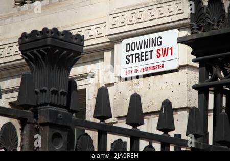 Enseigne de rue Enameled Downing SW1 vue à travers la clôture de protection en métal à l'extérieur du 10 Downing Street Londres Royaume-Uni Banque D'Images
