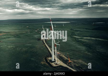 L'éolienne interprète au coucher du soleil. Installation des pales de rotor sur l'éolienne Banque D'Images