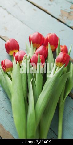 Image verticale de la vue en hauteur d'un bouquet de tulipes rouges sur des planches en bois Banque D'Images