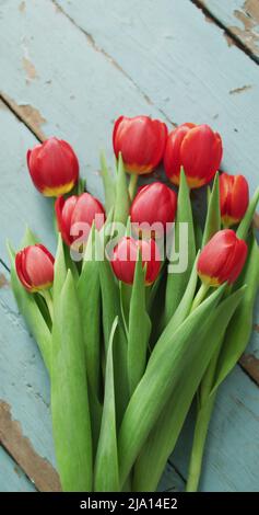 Image verticale de la vue en hauteur d'un bouquet de tulipes rouges sur des planches en bois Banque D'Images