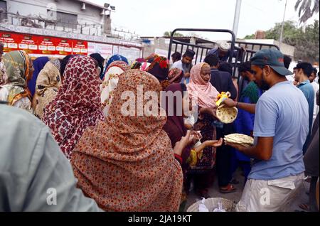 Rawalpindi, Pakistan, 26 mai 2022. Les personnes dans le besoin sont rassemblés dans une file d'attente pour obtenir des aliments de charité fournis par l'organisation caritative en raison de la hausse des prix dans le pays, à l'extérieur de l'hôpital Jinnah à Karachi le jeudi 26 mai 2022. Banque D'Images