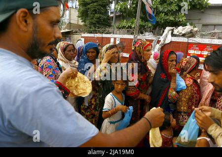 Rawalpindi, Pakistan, 26 mai 2022. Les personnes dans le besoin sont rassemblés dans une file d'attente pour obtenir des aliments de charité fournis par l'organisation caritative en raison de la hausse des prix dans le pays, à l'extérieur de l'hôpital Jinnah à Karachi le jeudi 26 mai 2022. Banque D'Images