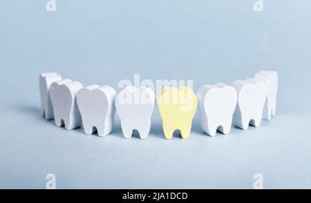 Dents en forme de sourire avec une dent malade jaune avec plaque sur fond bleu. Conséquences de la cavité, de la décomposition. Mauvaise hygiène buccale, problèmes dentaires, concept de stomatologie. Photo de haute qualité Banque D'Images