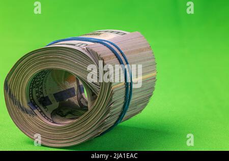 Vue rapprochée d'une pile de billets de 100 dollars en rouleau, isolée sur fond vert. Banque D'Images